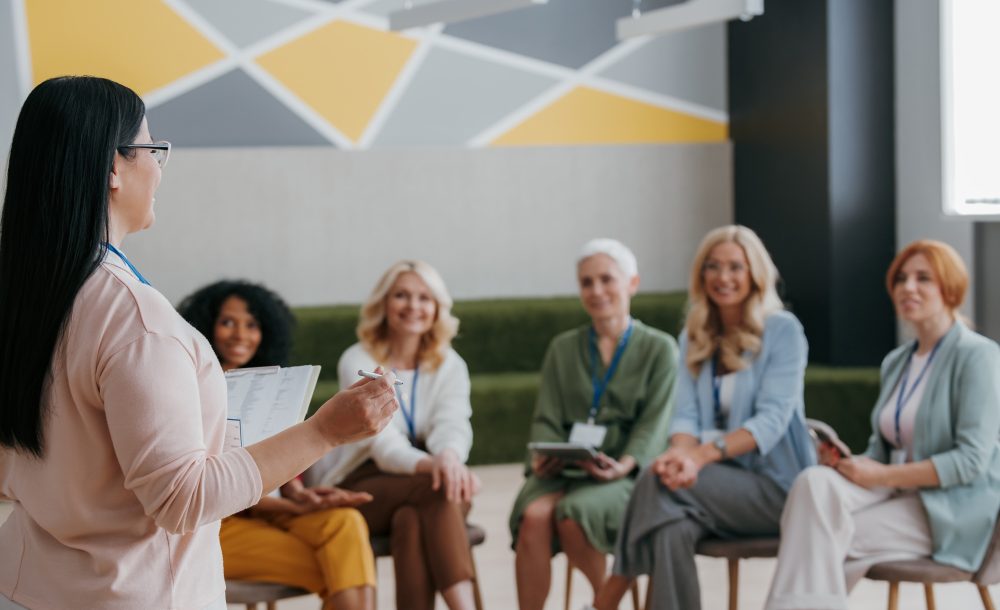Group of mature women listening to speaker while visiting training class together